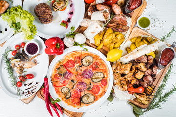 Big set of different dishes with meat, vegetables, pizza and spices flatlay on white background