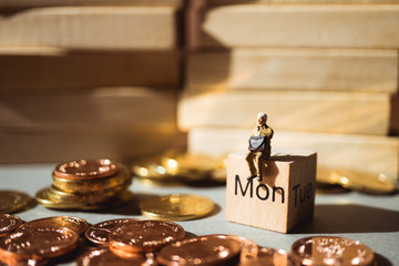 Miniature people, man sitting on monday wooden block and stack coins using as business concept