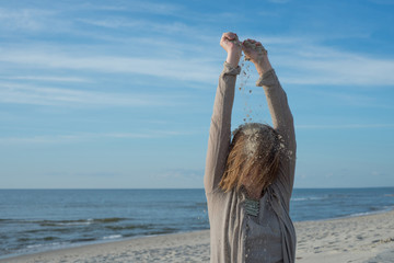 Woman pouring sand on her head on the beach