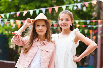 two smiling little girls of the girlfriend in the summer outdoors. kids celebrate birthday party together.