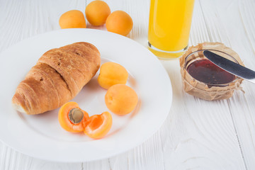 croissant, apricot, jam and juice for breakfast