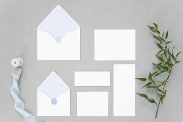 Feminine wedding, birthday desktop mock up. Blank greeting cards, envelope. Grey table background, blue envelopes and ribbon. Flat lay, top view.
