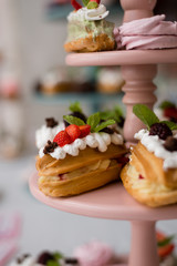 Appetizing eclairs with fruits and berries on the table