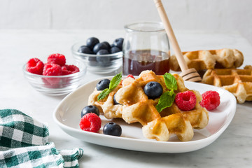 Traditional belgian waffles with blueberries and raspberries on white marble