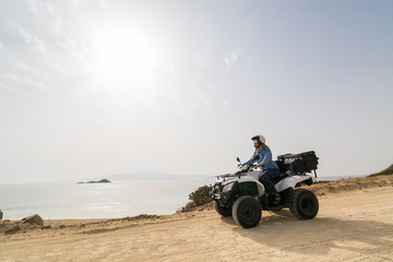 Young woman driving rental ATV quad bike on seaside road in Naxos island, Greece © oleksii.leonov