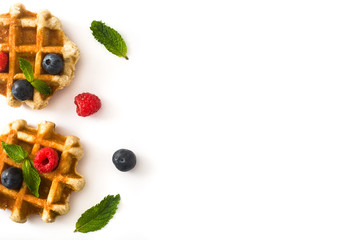 Traditional belgian waffles with blueberries and raspberries isolated on white background. Top view. Copyspace