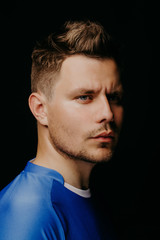 Fototapeta premium Close-up portrait of young handsome football player soccer posing on black dark background.