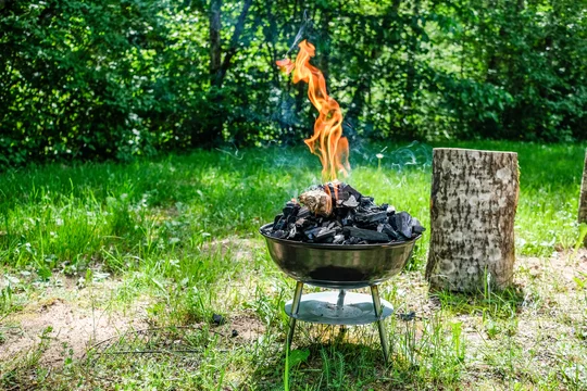 Fire on barbecue charcoal grill. Grilling food on a weber type small cheap BBQ grill at home. Stock-foto | Stock