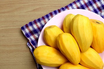 Ripe mango  in a pink plate on a wooden background.
