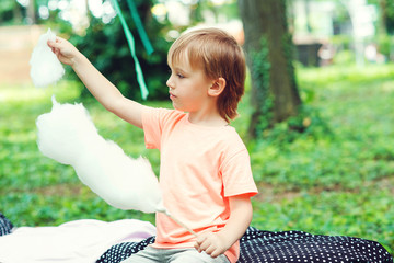 cute little boy eats candy-floss outdoors