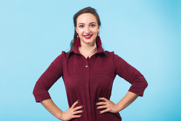 Beautiful smiling woman with clean skin, natural make-up, and red lips on blue background with copy space