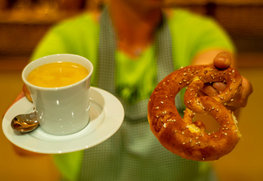 Verk&uuml;ferin bietet einen Kaffee und eine Bretze zum Fr&uuml;hst&uuml;ck an