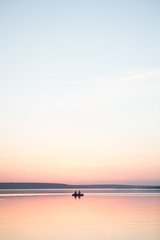Couple in a boat in a lake or pond or river in a sunset calm water no wind summer minimalism silhouette people beautiful meditation tourism outdoor meditation life happiness