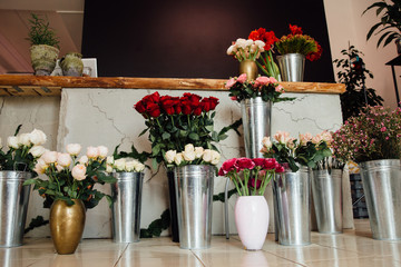counter of the flower shop is filled with zinc vases with bouquets of various colors.