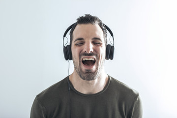 young man on a white background sings his favorite song while listening to music with headphones