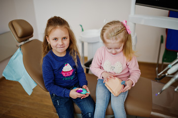 Two cutie little baby girls at dentist chair. Children dental.