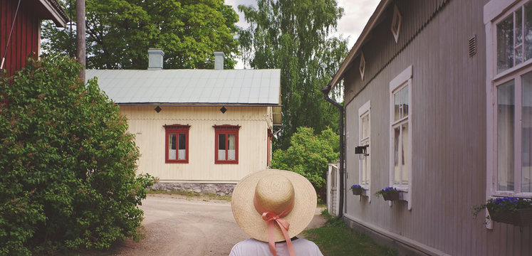 Girl Wearing A Summerhat Walking In A Smalltown In Summer