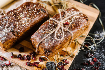sweet and tasty bread and wheat on black wooden background