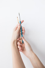 Two paint brushes in women hands on white background isolated