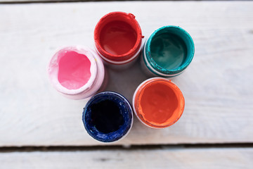 Different color paints in small jars on the white wood background art