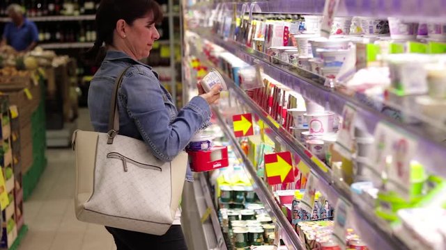Donna caucasica di mezza et&agrave; acquista cibo al supermercato. Decisione prodotti