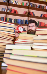 Deadline concept. Man on strict face looking at clock, bookshelves on background. Teacher or...