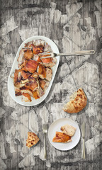Roasted pork shoulder slices with domestic leavened flatbread served on old rustic weathered...