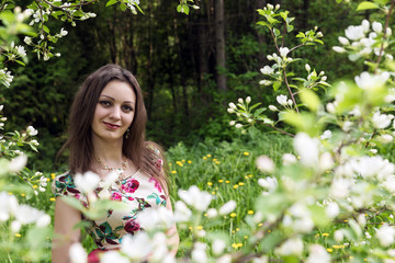 A girl with dark hair against the background of blooming trees in the park