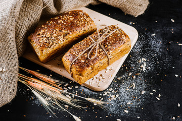 Sweet rye bread with different ingredients on black wooden background