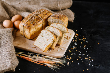 Sweet rye bread with different ingredients on black wooden background