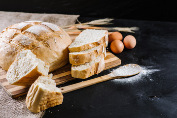 Sweet fresh bread with ingredients on black wooden background