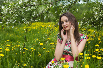 A girl with dark hair against the background of blooming trees in the park