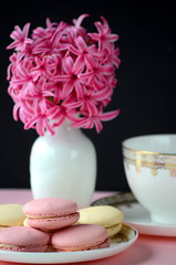 Bright pink hyacinth with French macarons, cup of coffee and gold black stationery. Female and lifestyle business and work from home concept. Spring theme. 