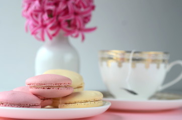 Fototapeta na wymiar Bright pink hyacinth with French macarons, cup of coffee and gold black stationery. Female and lifestyle business and work from home concept. Spring theme. 