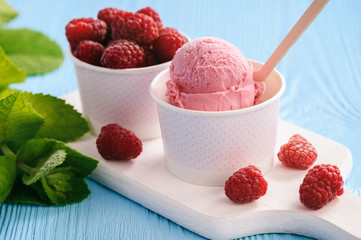 Vanilla and raspberry ice-cream on blue wooden background.