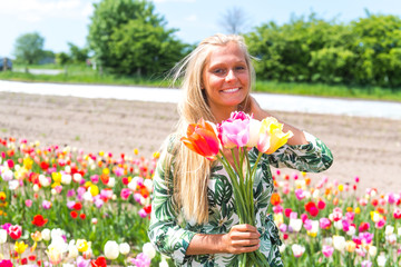 Obraz na płótnie Canvas Junge Frau pflückt Blumen auf einem Feld