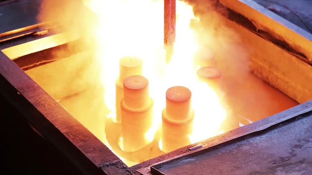 Hot metal ingot being loaded into water. Hardening in a factory