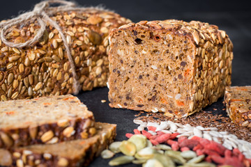 Tasty sweet rye bread with seeds on black wooden background