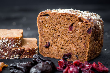 Tasty sweet rye bread with seeds on black wooden background