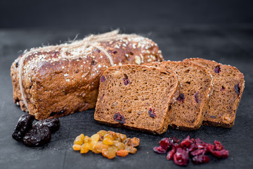 Tasty sweet rye bread with seeds on black wooden background