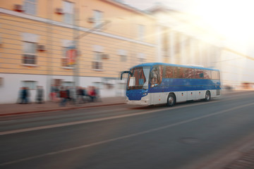 Excursion city bus moves along large city street. Motion blur. Sunny day