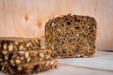 Tasty sweet rye bread with seeds on black wooden background