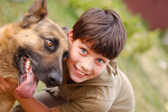 Happy Boy Smiles And Hugs A Big Dog - German Shepherd Dog