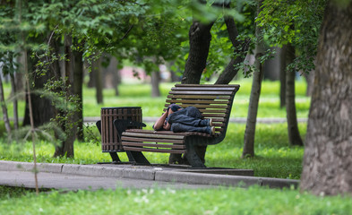 man is sleeping on a park bench