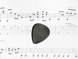 Guitar pick on note sheet with tabs
