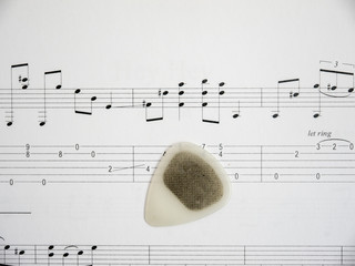 Guitar pick on note sheet with tabs