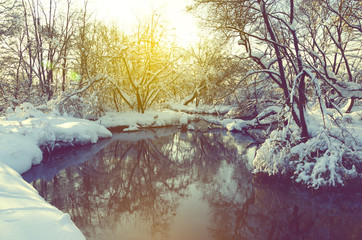 Fantastic winter landscape.Frosty scene with flowing forest river on a sunny morning.Beautiful snow covered trees in the glow of rising sun.