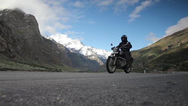 A motorcyclist passes  by camera in Ladakh, India