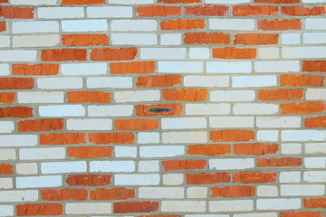 The wall of the house is made of white and red brick in the form of a pattern. Background.