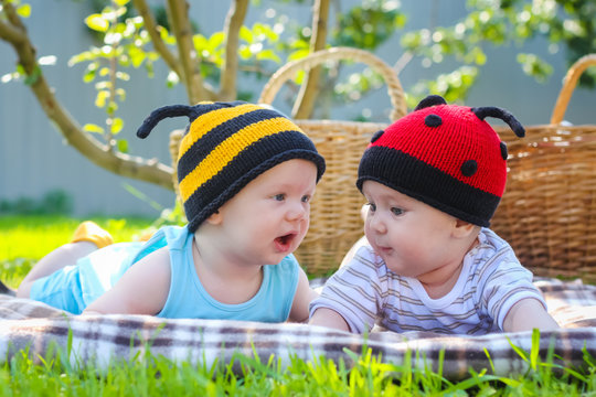 Little girl in knitted ladybird hat and boy playing outdoors, best friends, happy family, love and happiness concept